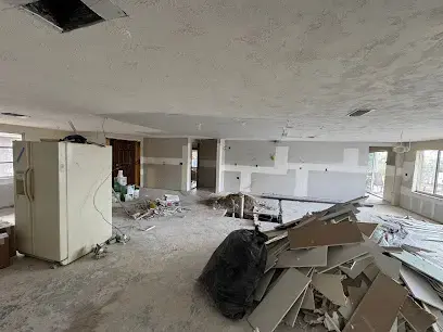 Open-plan room with wet drywall removed and debris bagged during a Florida flood cleanup